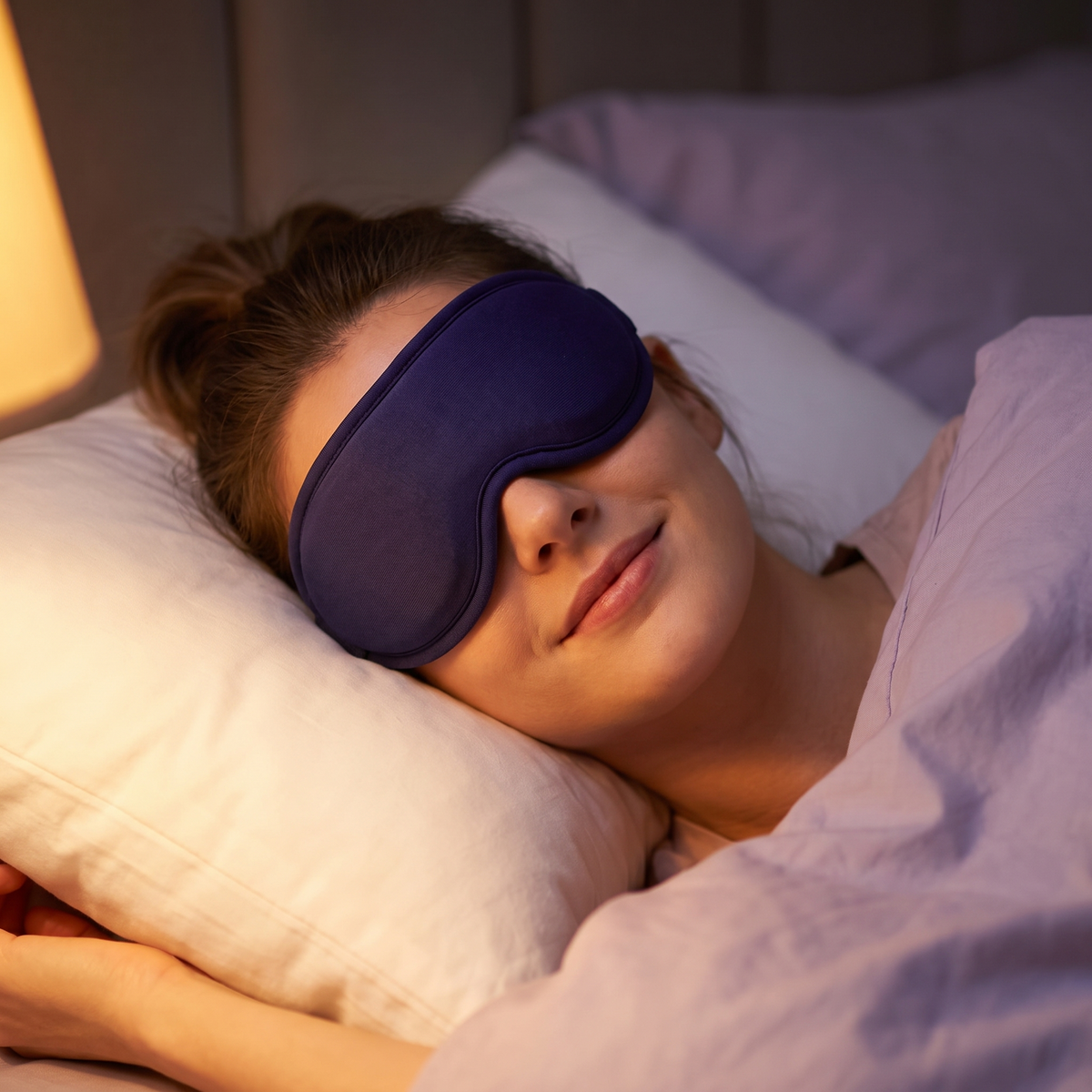 Femme apaisée au lit portant le masque chauffant Soirelle